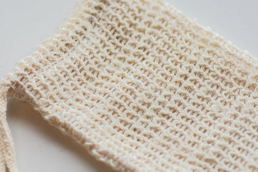 A close-up shot showing details of a woven beige soap net. 