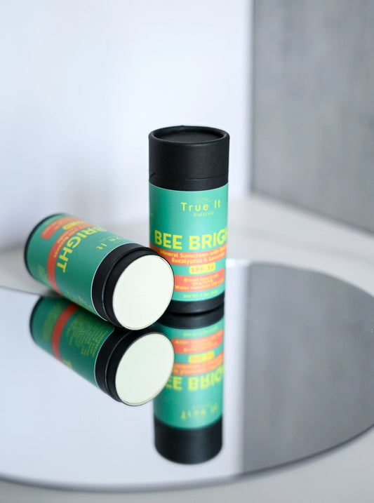 Two Bee Bright Sunscreen sticks sit on a mirrored background. 