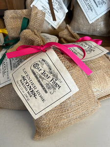 A burlap sack-style bag is positioned close to the camera. It is tied with a bright pink ribbon and a label that reads "Elf Leaf Farm Lavender Rose Scones".