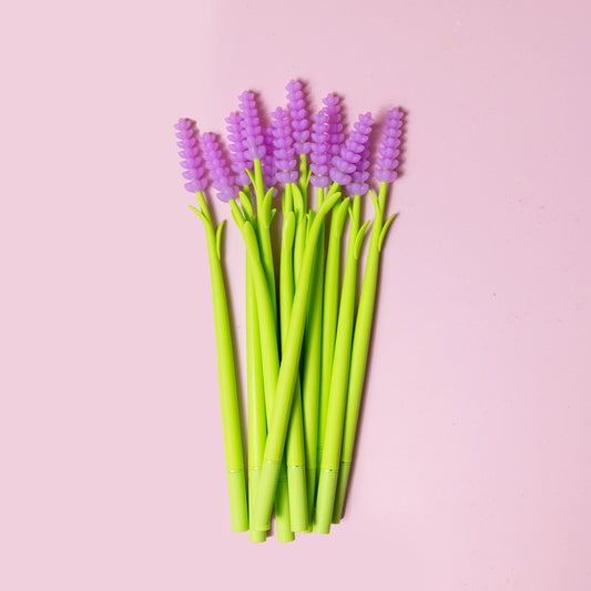 Eight pens shaped like lavender flowers sit on a pink background. 