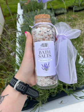 Bottle of bath salts with a label held by a hand against a natural background