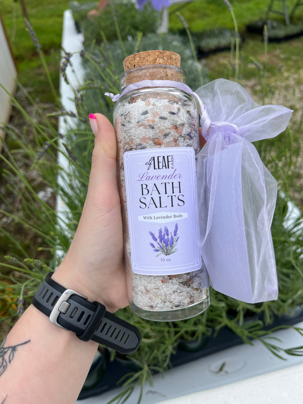 Bottle of bath salts with a label held by a hand against a natural background
