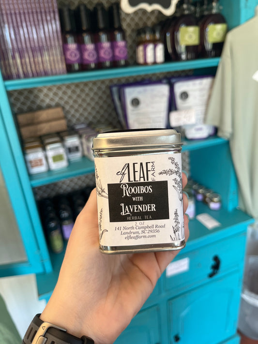 A person holds a container of Rooibos with Lavender Loose Leaf Tea in their hand. 