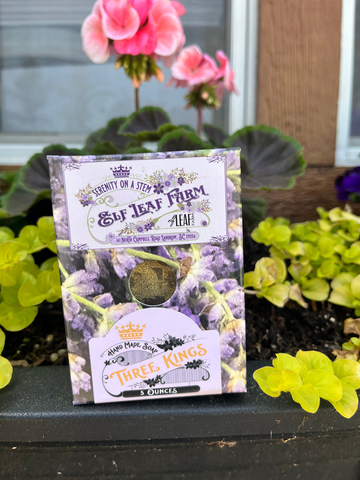 A bar of Elf Leaf Farm Three Kings Soap sits in front of fresh flowers. 